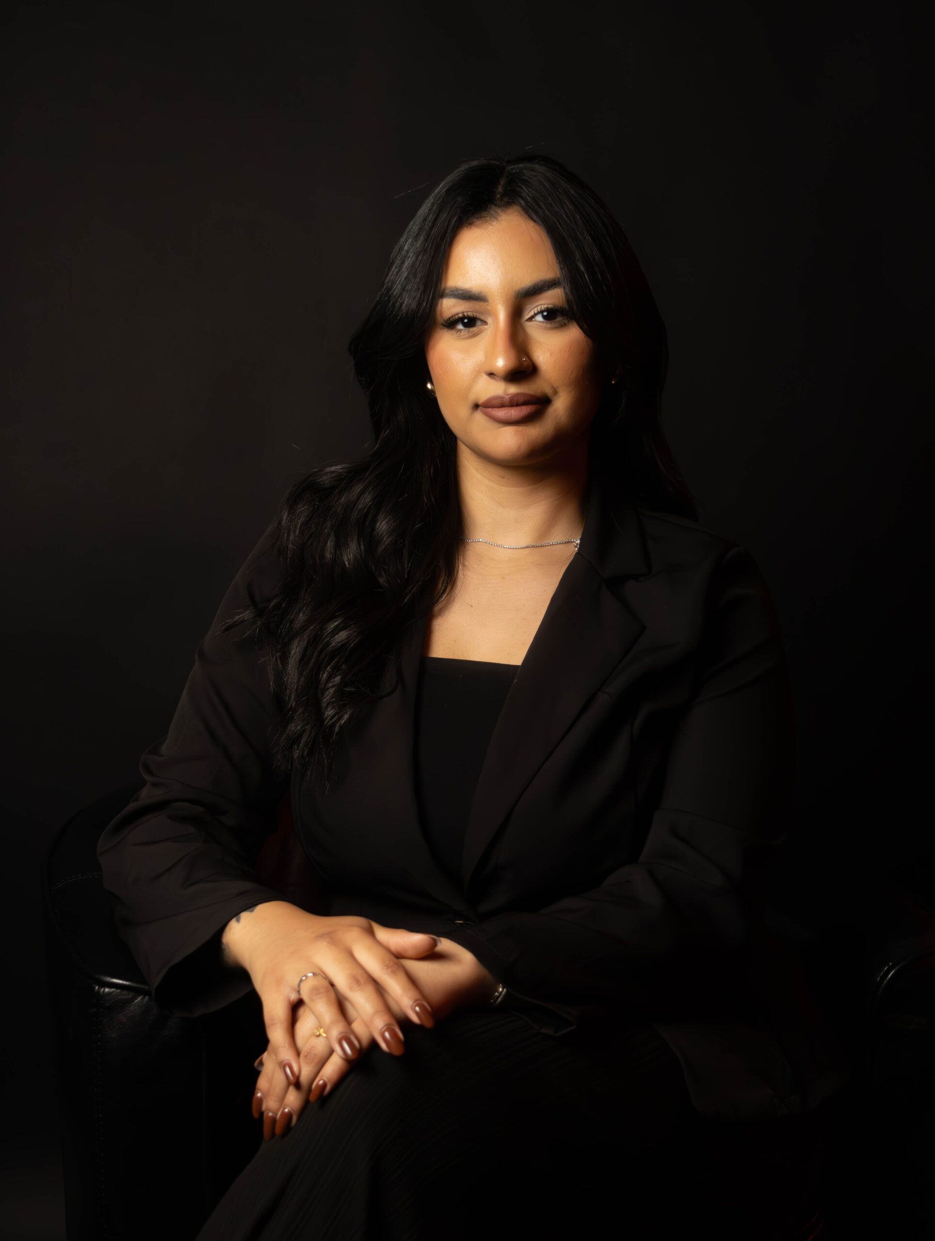 Portrait of a confident business woman in formal attire against a dark background.